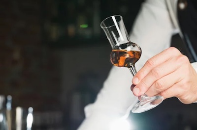 Homme tenant un verre contenant du rhum procédant à un examen visuel.